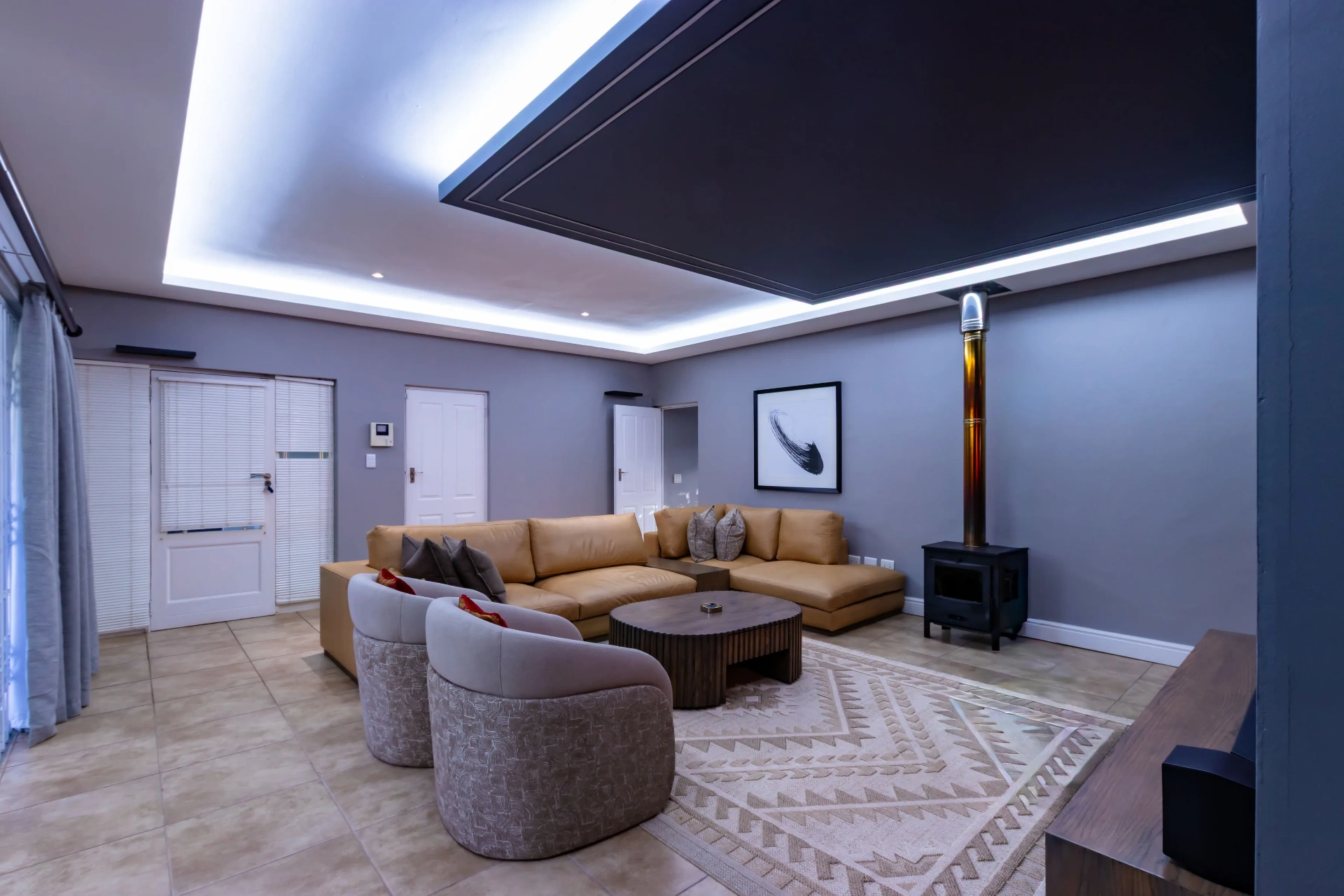 Lounge with tan leather sectional and wood stove